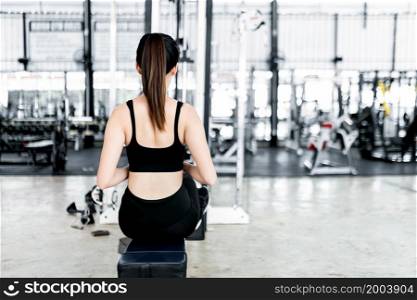 exercise concept The back side of exercising woman who has got brown ponytail hair taking the seat roll machine for her strength.
