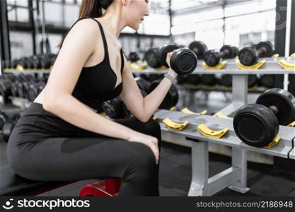 exercise concept The beginner of exercise picking the dumbbell and doing left concentration curl while perching on the black seat.