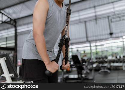 exercise concept The hefty man with his grey sport top and black pants standing still, grabbing the rope and pulling it downward.