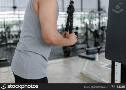 exercise concept The hefty man with his grey sport top and black pants standing still, grabbing the rope and pulling it downward.