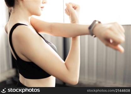 exercise concept The lady who has got black hair and wears a grey smartwatch doing arm stretching by support her left arm with the wrist of her right arm.