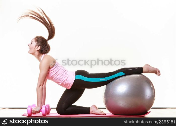 Exercise sport fitness health concept. Fit girl exercising. Attractive female warming up with ball and dumb bell weights.. Girl warming up with ball and dumb bell weights.
