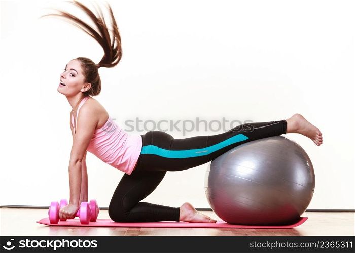 Exercise sport fitness health concept. Fit girl exercising. Attractive female warming up with ball and dumb bell weights.. Girl warming up with ball and dumb bell weights.
