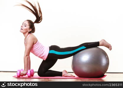 Exercise sport fitness health concept. Fit girl exercising. Attractive female warming up with ball and dumb bell weights.. Girl warming up with ball and dumb bell weights.