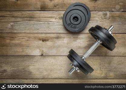 exercise weights - iron dumbbell with extra plates on a wooden deck