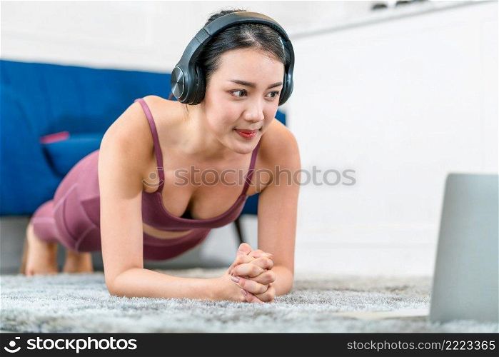 Exercises at home concept, Asian woman practicing yoga at home with laptop and using earphone for listend the music for relax