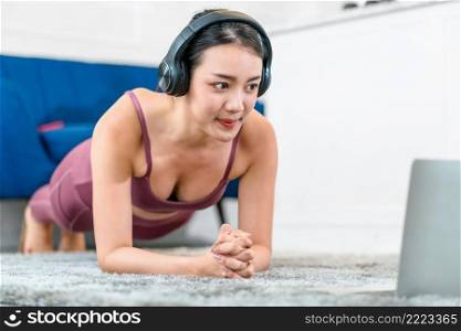 Exercises at home concept, Asian woman practicing yoga at home with laptop and using earphone for listend the music for relax