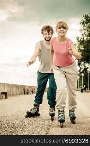 Exercising and competition in sport. Healthy lifestyle and wellbeing. Summertime hobby. Young people race together on rollerblades having fun.. Two people race together riding rollerblades.