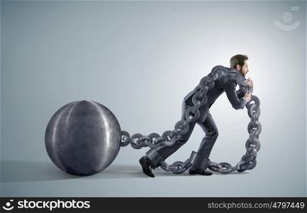 Exhausted businessman dragging heavy chains