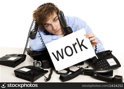 Exhausted man full of work, sitting with a bunch of phones over him and holding a cardboard with the word Work.