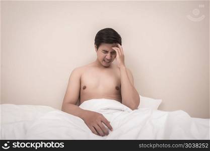 Exhausted man sitting on his bed with his hand on head.. Exhausted man sitting on his bed with his hand on head.
