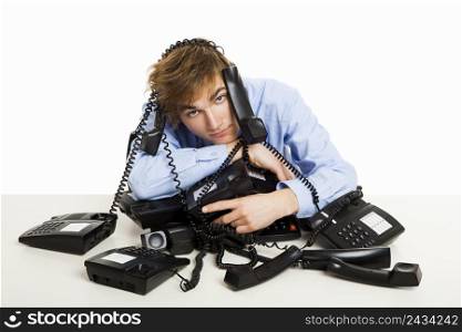 Exhausted man sitting with a bunch of phones over him