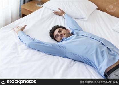 Exhausted young businessman lying in bed