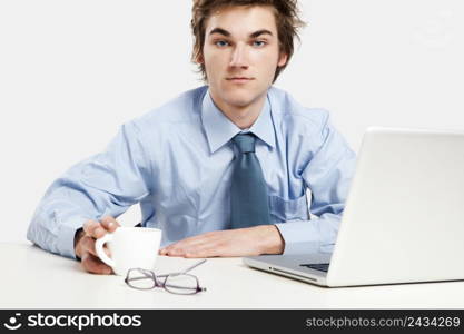 Exhausted young man in the office with the laptop on his front