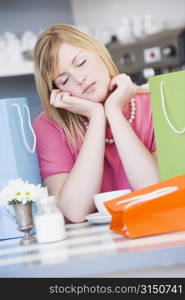 Exhausted young woman sitting at a table taking a break from shopping