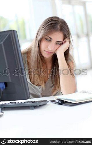 Exhausted young woman sitting in front of computer