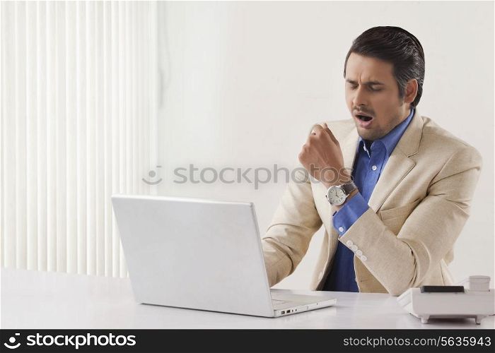 Exhaustion young businessman using laptop at office desk