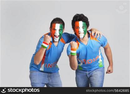 Exhilarated male cricket supporters with a painted face in tricolor cheering over colored background