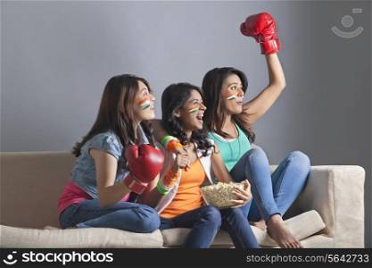 Exhilarated young women watching boxing match together at home