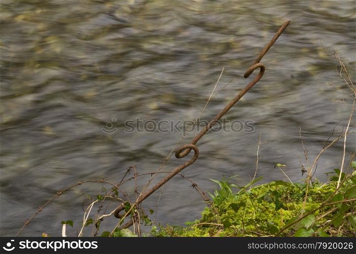 Existing remains of barbed wire entanglement, wire and picket posts, river in background. Long exposure. Part of Carmarthen stop line, Wales, United Kingdom.