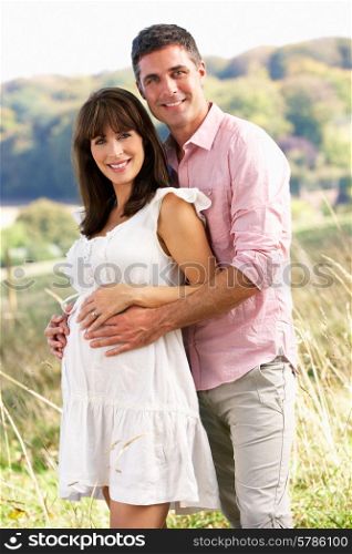 Expectant couple outdoors in countryside