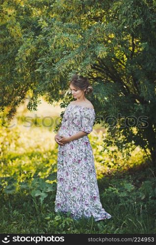 Expectant mother waiting for a miracle walks through the garden.. Portrait of a pregnant girl walking in the summer garden 1648.