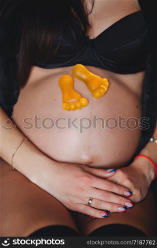 Expectation of the child. A pregnant woman sitting with toy feet.. Expectation of the child. A pregnant woman sitting with toy feet. Motherhood Concept.