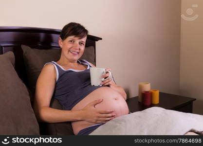 Expecting mother enjoying her coffee in her bedroom