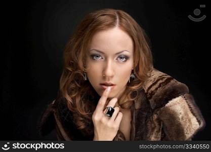 Expensively dressed beautiful woman on a black background
