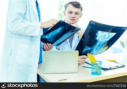 Experience male and female doctors orthopedics and team expert discussing x-ray film, surgery with the interpretation an x-ray in operating room in hospital .Medical technology and health care concept