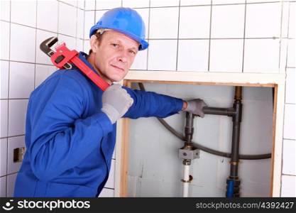 Experienced plumber using a large wrench in a bathroom