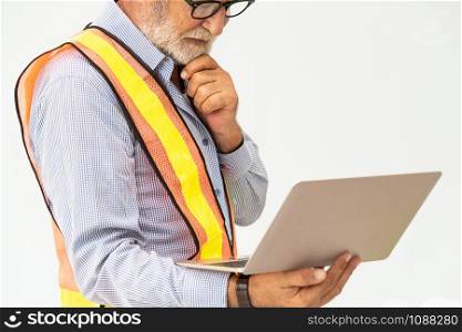 Experienced senior foreman or engineer using laptop computer standing against white background. Construction and engineering concept.