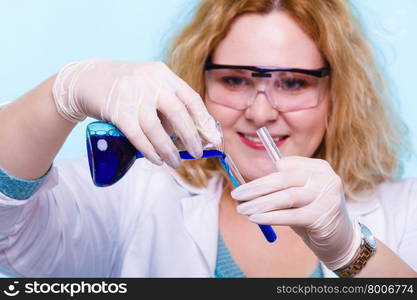 Experiment, research in progress. Chemist woman or student girl, laboratory assistant or scientific researcher with chemical glassware test flask on blue