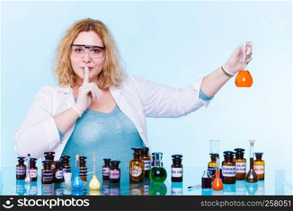 Experiment, research in progress. Chemist woman or student girl,scientific researcher with chemical glassware test flask hand silence sign, saying hush be quiet.