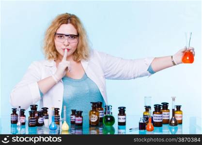 Experiment, research in progress. Chemist woman or student girl,scientific researcher with chemical glassware test flask hand silence sign, saying hush be quiet.