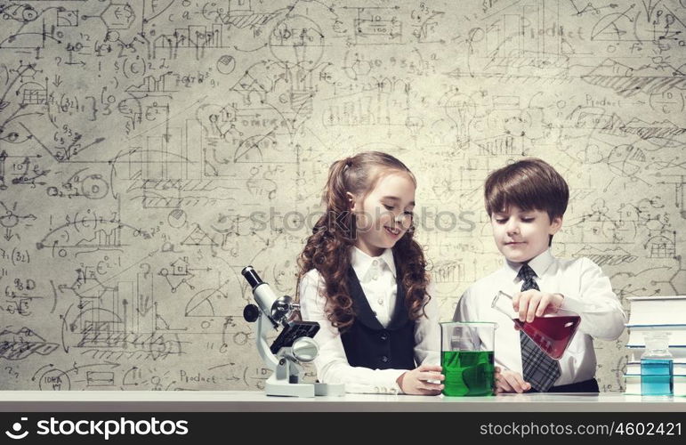 Experiments in laboratory. Cute girl and boy at chemistry lesson making tests