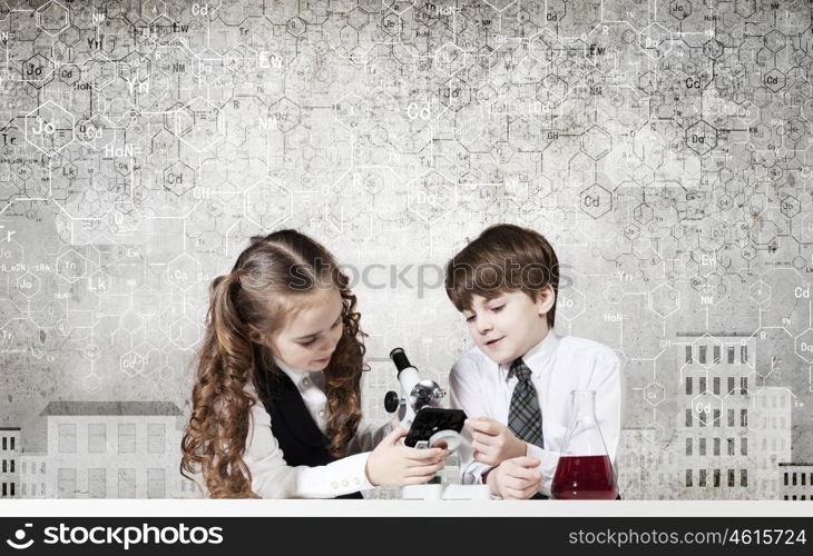 Experiments in laboratory. Cute girl and boy at chemistry lesson making tests