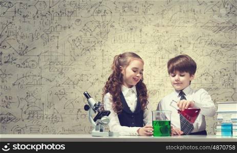 Experiments in laboratory. Cute girl and boy at chemistry lesson making tests