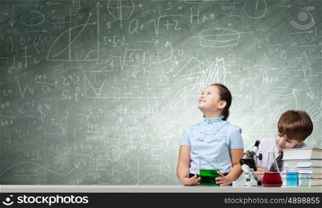 Experiments in laboratory. Cute girl and boy at chemistry lesson making tests