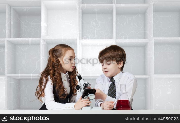 Experiments in laboratory. Cute girl and boy at chemistry lesson making tests