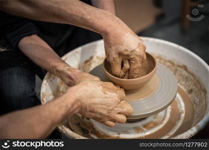 Expert potter teach a man to work on potter wheel. Closeup of dirty hands