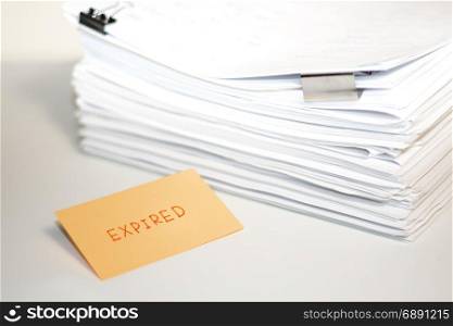 Expired; Stack of Documents on white desk and Background.