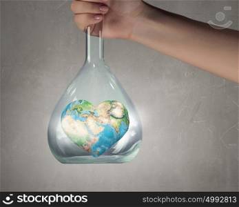Exploration of world and planet. Close up of human hand holding test tube with Earth planet. Elements of this image are furnished by NASA