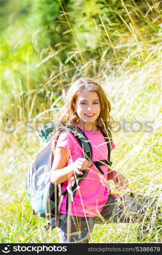 Explorer kid girl walking with backpack between forest grass
