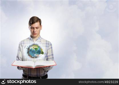 Exploring the world around us. Young man with opened book in hands. Elements of this image are furnished by NASA