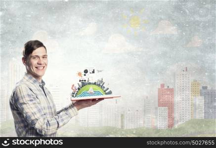 Exploring the world around us. Young man with opened book in hands and green concept on pages