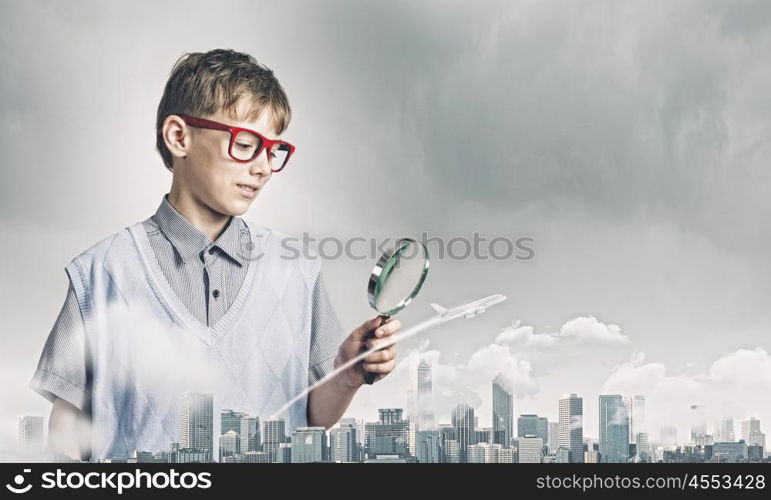 Exploring the world. Cute school boy examining objects with magnifying glass