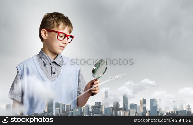 Exploring the world. Cute school boy examining objects with magnifying glass