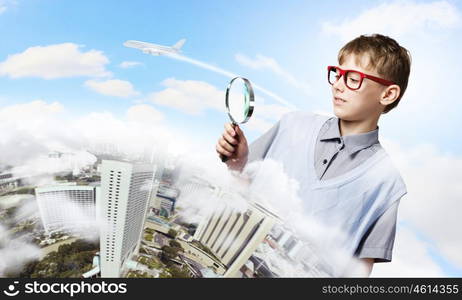 Exploring the world. Cute school boy examining objects with magnifying glass