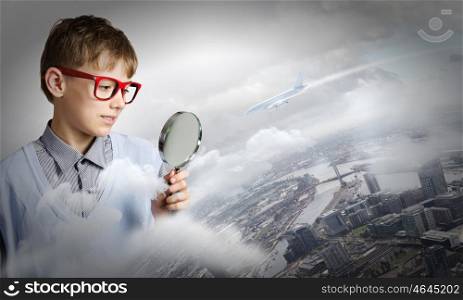 Exploring the world. Cute school boy examining objects with magnifying glass